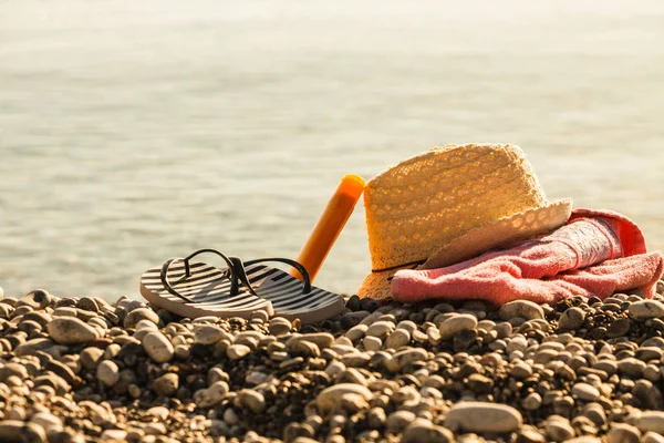 Czapka i klapki na kamiennej plaży — Zdjęcie stockowe