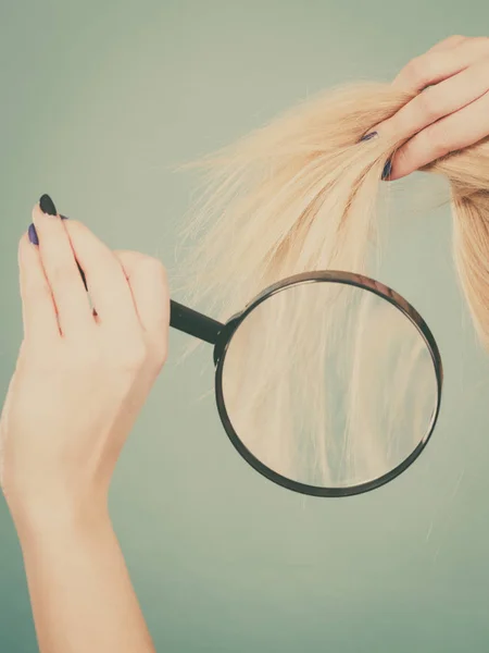 Женщина смотрит на волосы через увеличительное стекло — стоковое фото