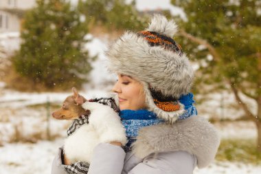 Küçük köpeğini kışın ısınma kadın kucaklama