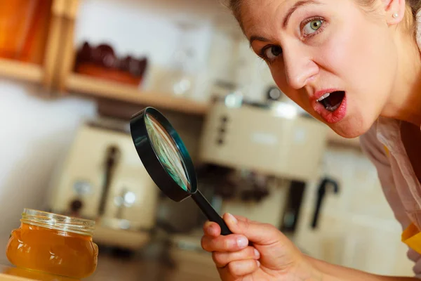 Mujer inspeccionando miel con lupa . — Foto de Stock