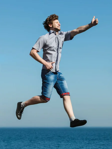 Carefree man jumping by sea ocean water. — Stock Photo, Image