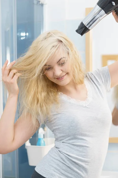 Mulher loira usando secador de cabelo — Fotografia de Stock