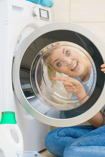 Mulher olhando para dentro da máquina de lavar roupa — Fotografia de Stock