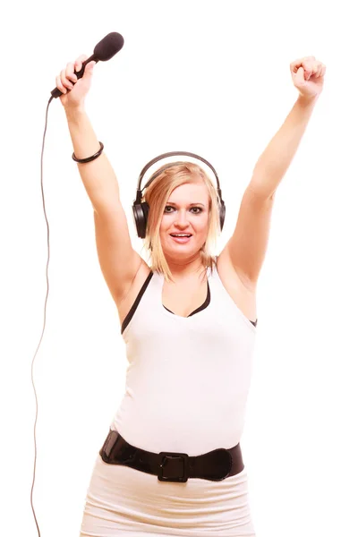 Woman singing to microphone wearing headphones — Stock Photo, Image
