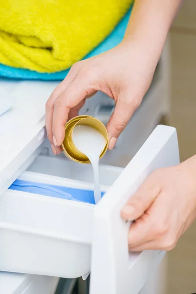 Person pouring fabric softener into washing machine — Stock Photo, Image