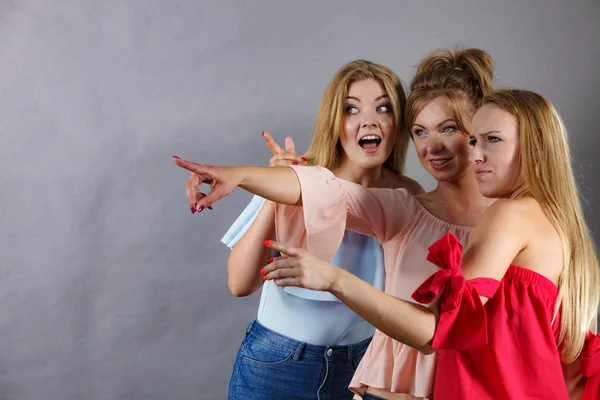 Three fashionable females pointing