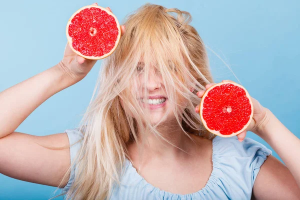 Woman holding red grapefruit having crazy windblown hair