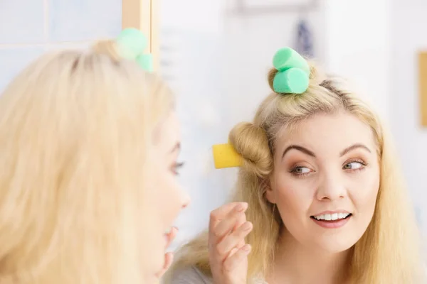 Blonde woman using hair rollers — Stock Photo, Image