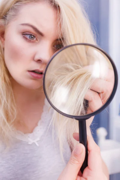 Femme regardant les extrémités des cheveux à travers la loupe — Photo