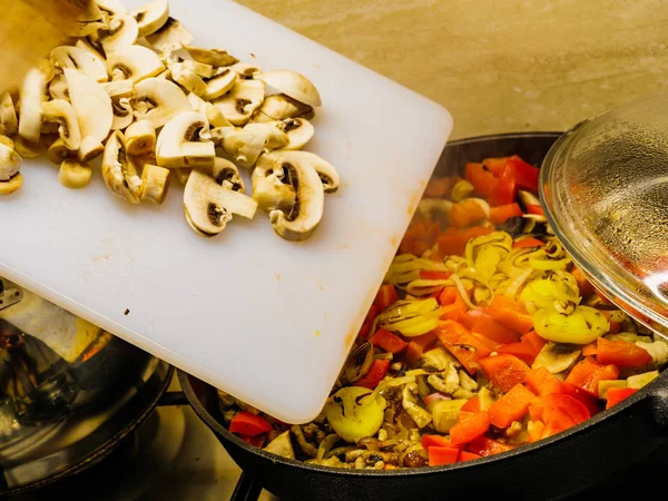 Ajouter des champignons à la casserole de légumes . — Photo