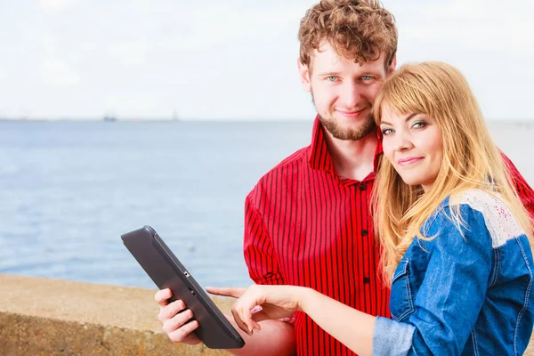 Young couple with tablet by seaside outdoor