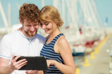 Genç tablet ile açık deniz kenarında çift.