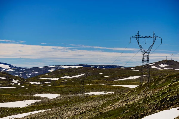 Power line spänning tower i bergen mot blå himmel — Stockfoto