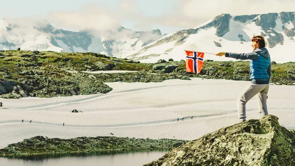 Tourist with norwegian flag in mountains