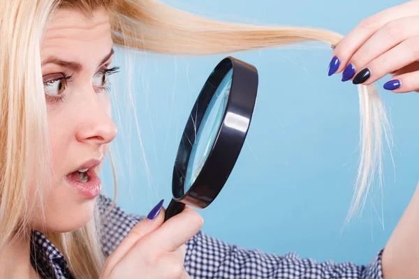 Femme regardant les cheveux à travers la loupe — Photo