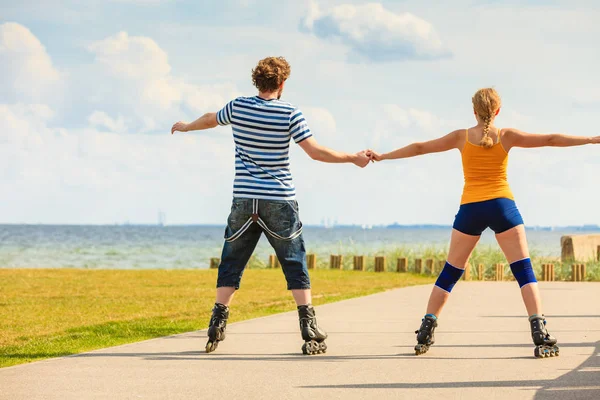 Jovem casal em patins andando ao ar livre — Fotografia de Stock