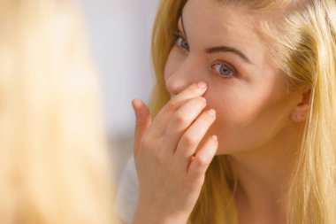 Bir kadın aynada tenine bakıyor.