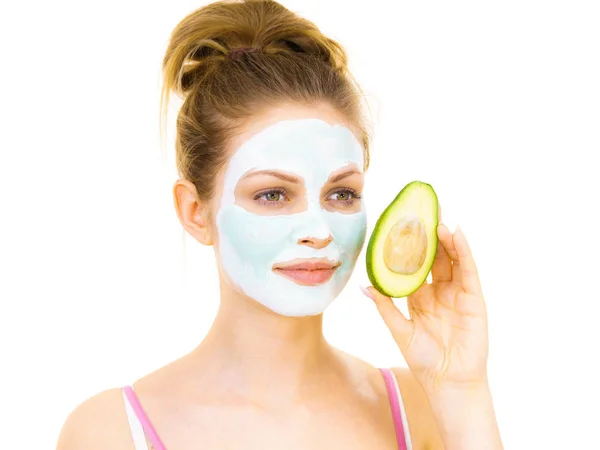 Girl facial mud mask holds avocado fruit — Stock Photo, Image