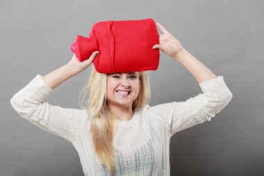 Kırmızı sıcak su şişesi üzerinde kafa tutan kadın