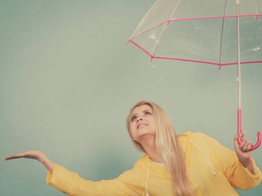Hava kontrol şemsiye tutan yağmurluk giyen kadın