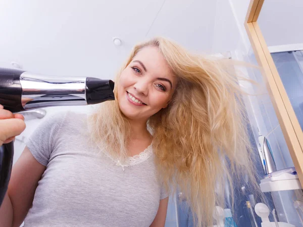Женщина сушит волосы в ванной комнате — стоковое фото
