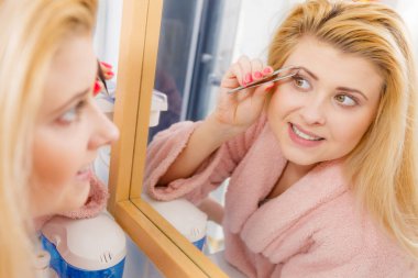 Kaşlarını cımbızla temizleyen kadın.