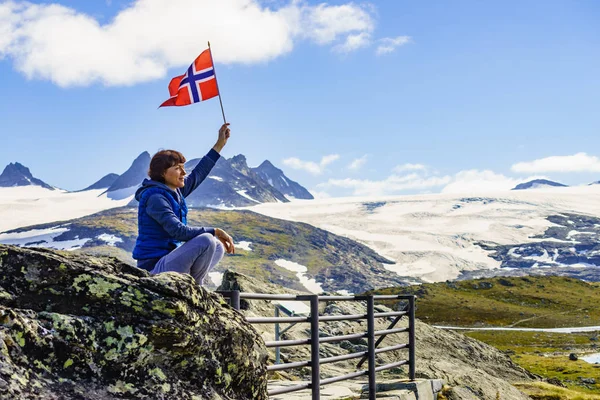 Tourist with norwegian flag in mountains