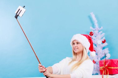 Santa şapka alarak fotoğrafını selfie stick kullanarak kız