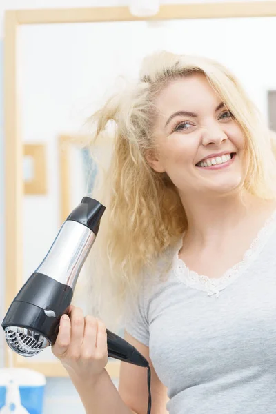 Mulher loira usando secador de cabelo — Fotografia de Stock