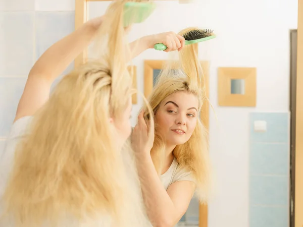 Mujer cepillándose el pelo rubio en el baño — Foto de Stock