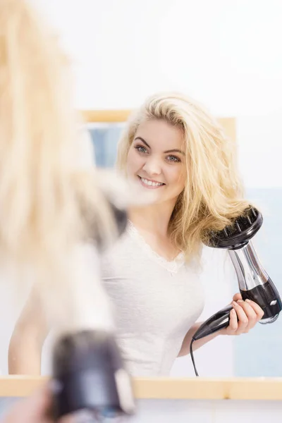 Blonde vrouw met behulp van een föhn — Stockfoto