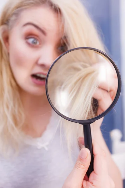 Femme regardant les extrémités des cheveux à travers la loupe — Photo