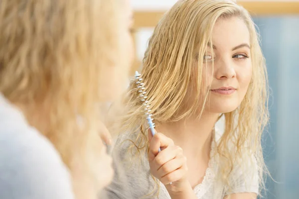 Woman brushing her wet blonde hair