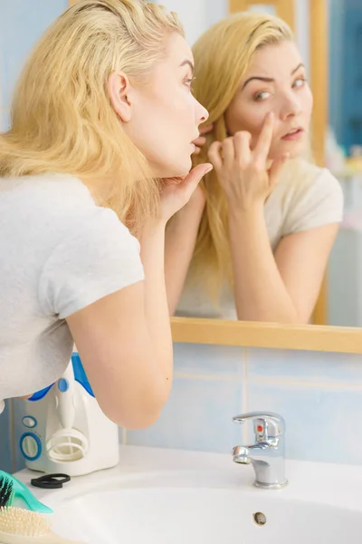 Mujer mirando su piel en el espejo — Foto de Stock