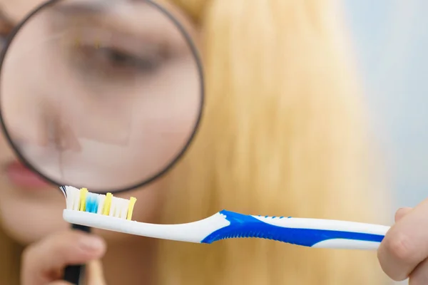 Mulher olhando escova de dentes através da lupa — Fotografia de Stock