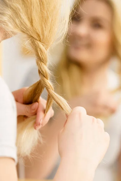 Woman making braid on blonde hair — Stock Photo, Image