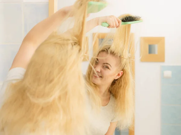Mulher escovando seu cabelo loiro no banheiro — Fotografia de Stock