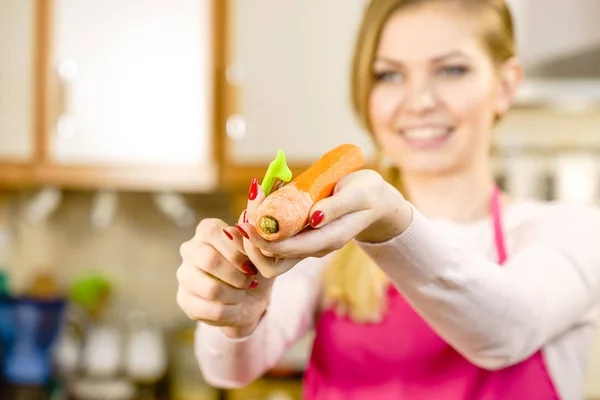 Женщина чистит морковный овощ — стоковое фото