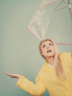 Hava kontrol şemsiye tutan yağmurluk giyen kadın