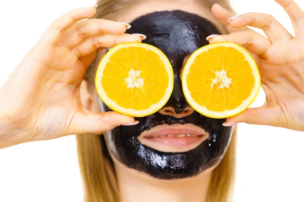 Girl black carbo mask on face holds orange fruit — Stok Foto