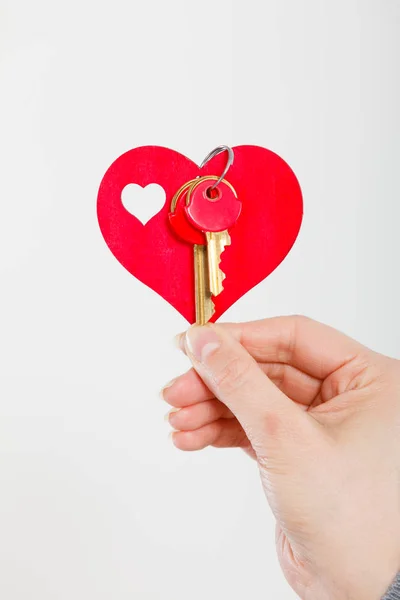 Női kéz tartja a kis szívét kulcsokkal. — Stock Fotó
