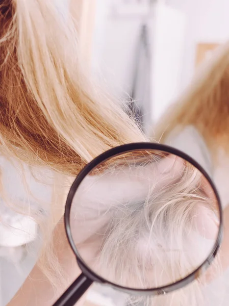 Woman looking at hair ends through magnifying glass — Stock Photo, Image