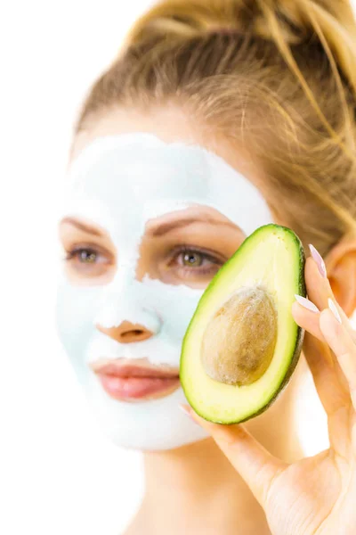 Meisje gezicht modder masker houdt avocado fruit — Stockfoto