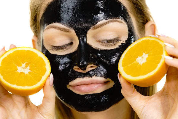 Girl black carbo mask on face holds orange fruit — Stok Foto