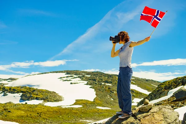 Turismo tiene fotocamera e bandiera norvegese in montagna — Foto Stock