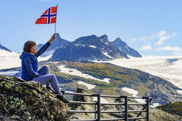 Tourist with norwegian flag in mountains