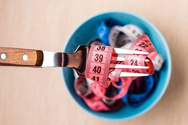 Many colorful measuring tapes in bowl on table — Stock Photo, Image