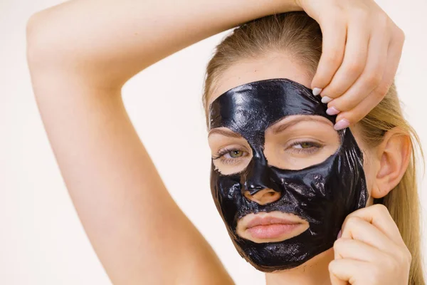 Девушка снимает черную маску с лица — стоковое фото