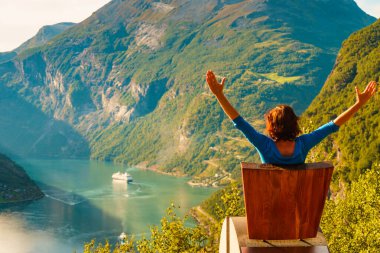 Tourist enjoy Geiranger fjord from viewpoint seat clipart