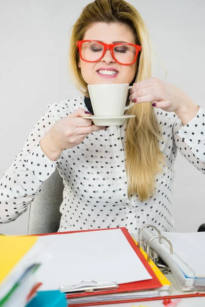 Femme heureuse au bureau buvant du café chaud — Photo